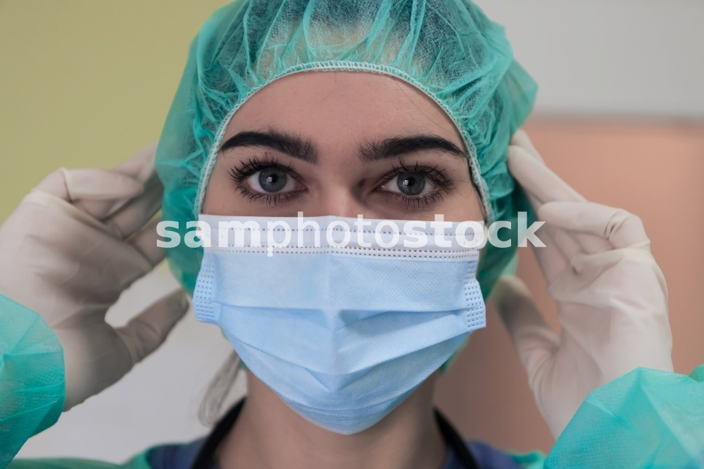 The female animal surgeon or veterinarian puts on a medical face mask. Doctor is preparing for surgery in the operation room. Medicine and healthcare. High quality photo. The female animal surgeon or veterinarian puts on a medical face mask. Doctor is preparing for surgery in the operation room. Medicine and healthcare